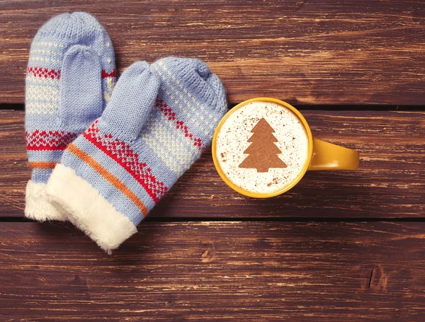 Mittens and cappuccino with christmas tree — Stock Photo, Image