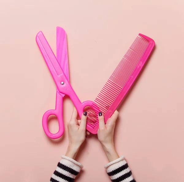Hand holding pink scissors and comb — Stock Photo, Image
