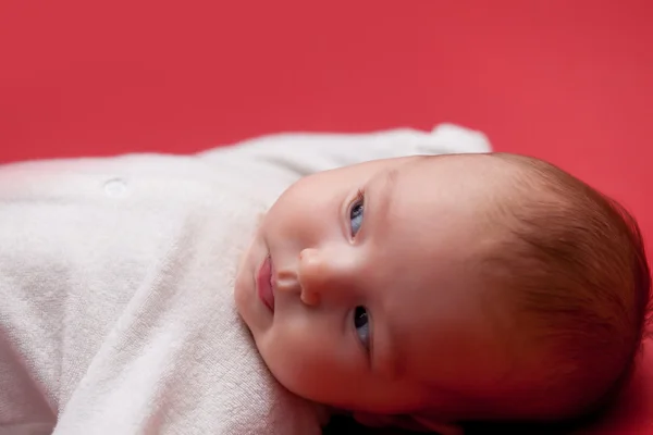 Baby på röd bakgrund — Stockfoto