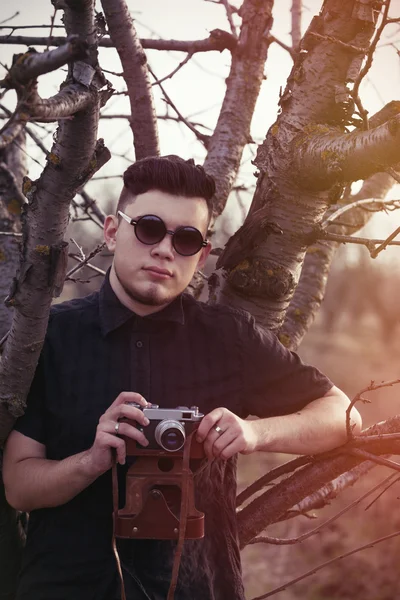 Jeune homme avec caméra vintage près de l'arbre — Photo