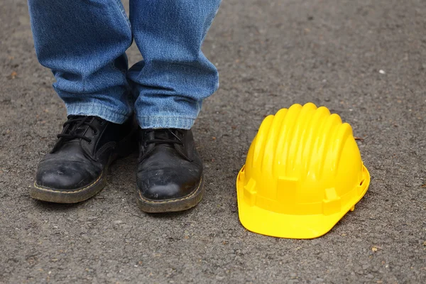 Foots next to a yellow helmet — Stock Photo, Image