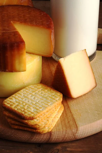 木製ボード上の黄色のチーズ クラッカーや牛乳のガラス — ストック写真