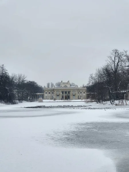 ポーランドのワルシャワにある公園の水の上の美しい歴史的な宮殿雪の冬の間 — ストック写真