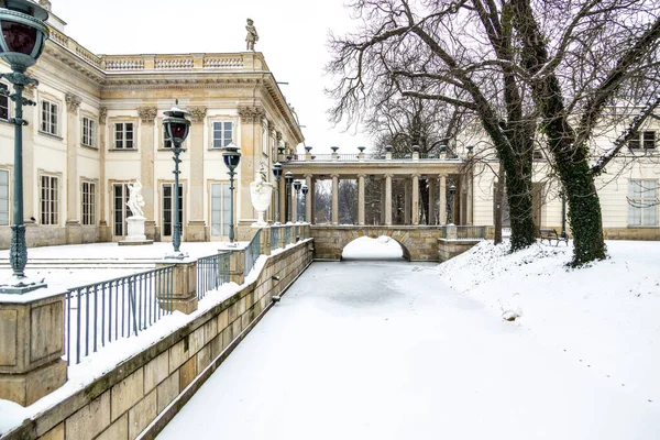 ポーランドのワルシャワにある公園の水の上の美しい歴史的な宮殿雪の冬の間 — ストック写真