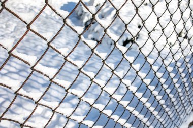 Metal örgü, beyaz kar arkaplanda çit kışın yakın planda.