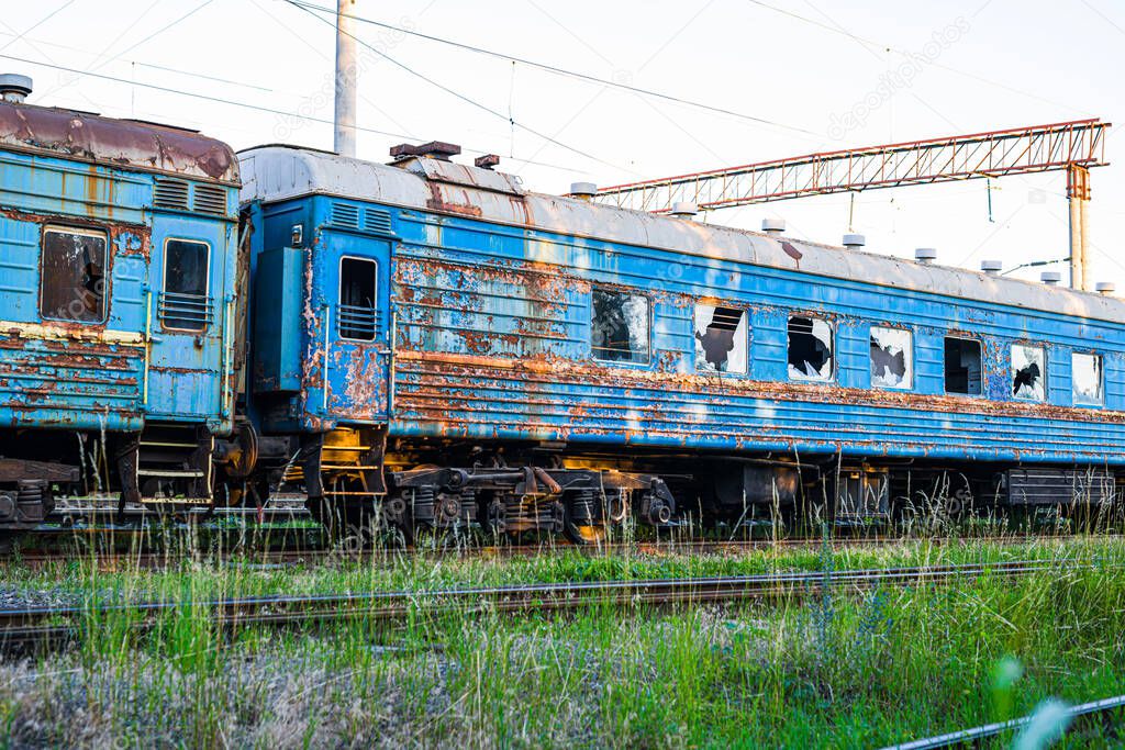 Old, rusty and abandoned blue passenger cars on the spare track of the railway