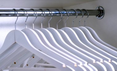 Dolaptaki ahşap beyaz elbise askıları.