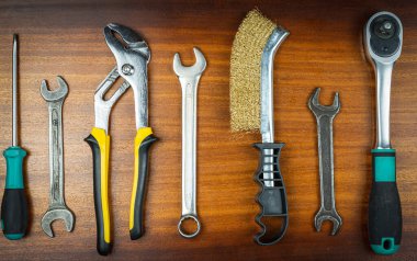 Farklı aletler - anahtarlar, tornavida, bıçak, metal fırça, kahverengi ahşap arka planda ev onarımı için kalem