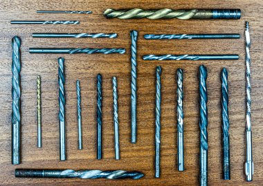 Kahverengi ahşap dokunun arka planında ahşap ve metal delmek için farklı çaplı matkaplar.