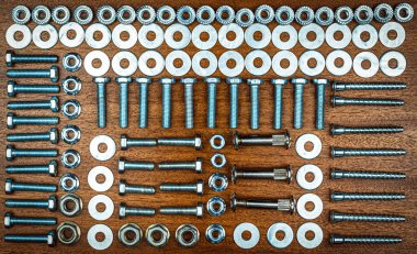 Düğüm stili fotoğraf - kahverengi ahşap arka planda çeşitli cıvatalar, fındıklar, yıkama ve vidalar