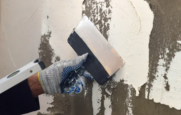 El proceso de aplicación de una masilla blanca en la pared de hormigón gris — Foto de Stock