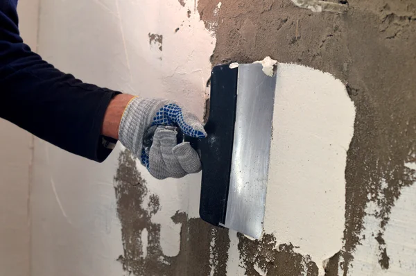 El proceso de aplicación de una masilla blanca en la pared de hormigón gris —  Fotos de Stock