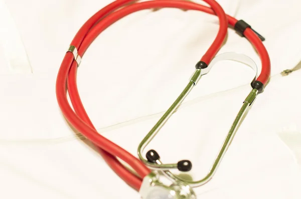 Medicinska Stetoskop för rött ljus mot en vit morgonrock — Stockfoto