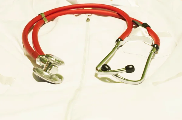 Medical stethoscope of red light against a white dressing gown — Stock Photo, Image