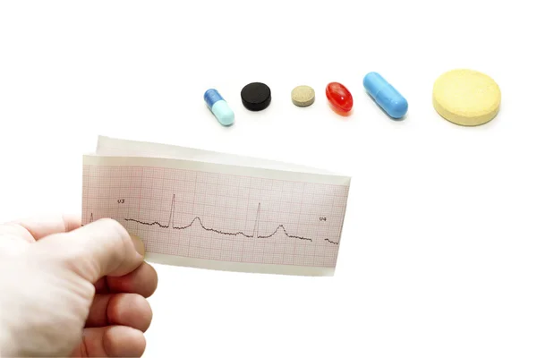 Electrocardiogram in hand different pills — Stock Photo, Image
