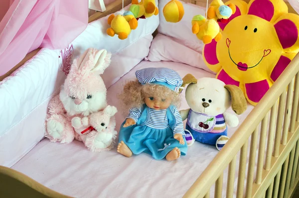 Différents peluches dans le lit bébé avec du lin orange — Photo