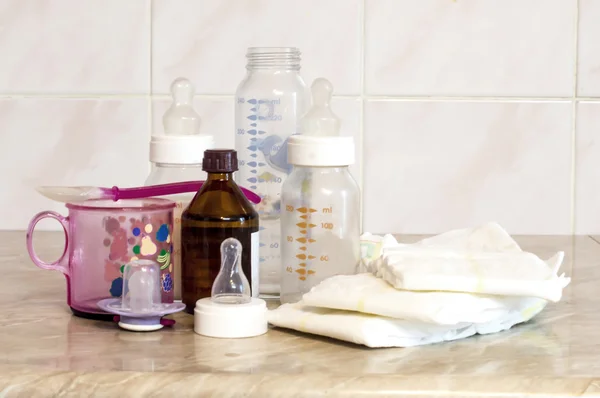 Different glass bottles with a mixture of feeding and baby diape — Stock Photo, Image