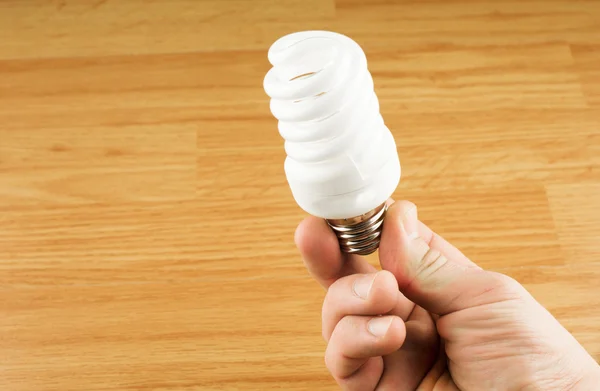 Luminescent light bulb in his hand — Stock Photo, Image