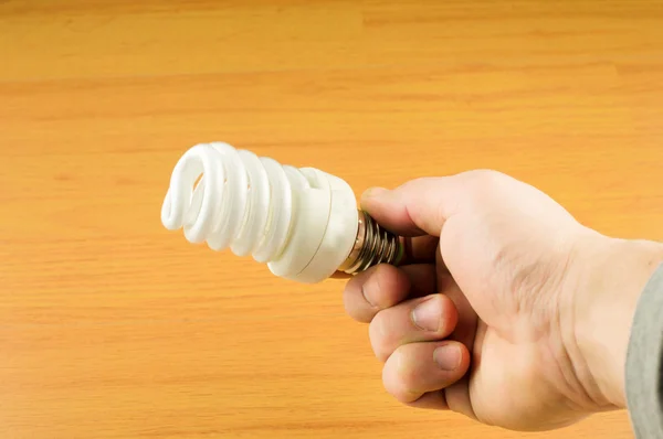 Luminescent light bulb in his hand — Stock Photo, Image