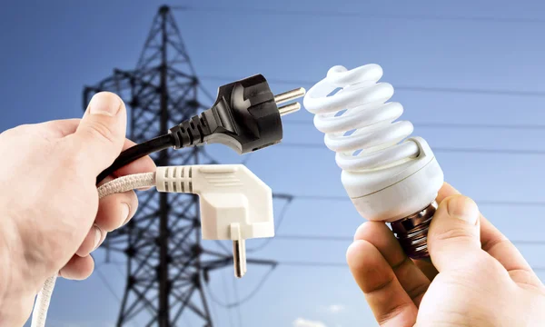 Fluorescent bulb and plug in the hands — Stock Photo, Image