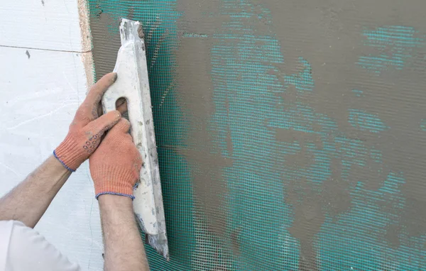 Aplicando massa de vidraceiro na parede usando uma espátula — Fotografia de Stock