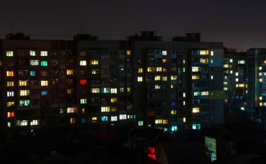 Büyük bir şehirde gece yarısı pencereleri açık olan bir apartman.