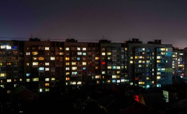 Büyük bir şehirde gece yarısı pencereleri açık olan bir apartman.