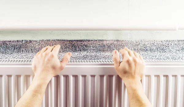 Warming hands near the aluminum radiator — Stock Photo, Image