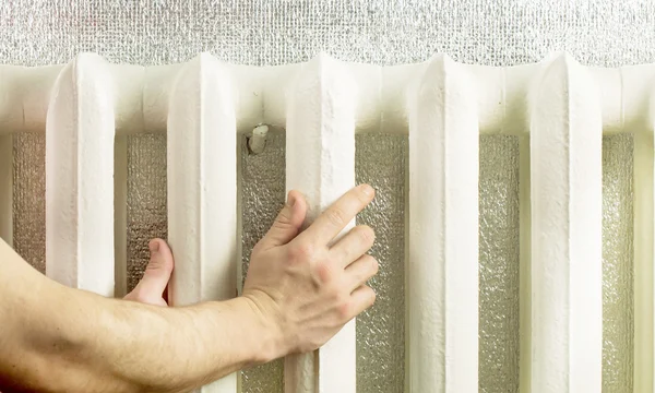 Opwarming van de aarde handen in de buurt van de ijzer-radiator — Stockfoto