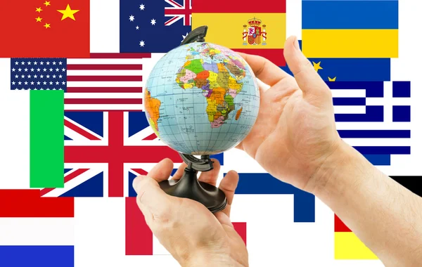 Globo en las manos sobre un fondo de banderas de todo el mundo — Foto de Stock