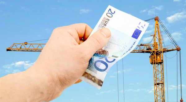 Euro in hand on a background building crane — Stock Photo, Image