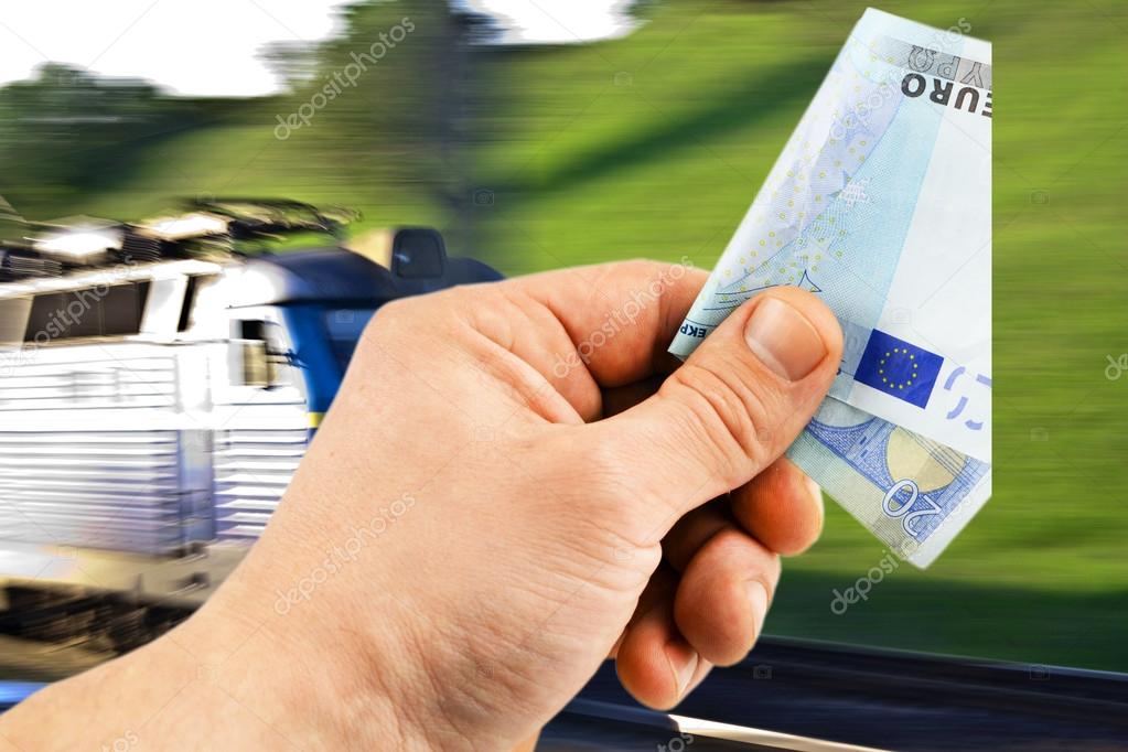 The euro in his hand on a background of train 