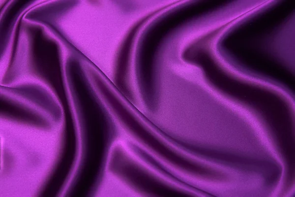 Close-up texture of natural violet fabric or cloth in same color. Fabric texture of natural cotton, silk or wool, or linen textile material. Red and orange canvas background.