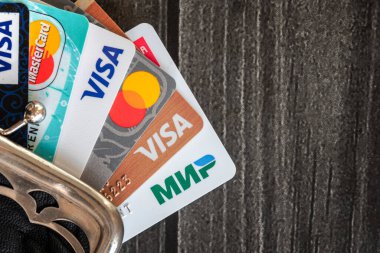 Moskova, Rusya, 17 Ocak 2021 - Tahta masadaki eski deri cüzdan kutusunda az sayıda kredi kartı (Visa, Mastercard ve Mir), ürün konsepti atışı.