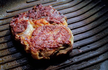 Izgara tavada ızgara demir biftek, mermer biftek. Gri arka plan. Üst görünüm