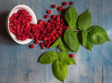 Mavi ahşap masada kasede taze ahududu. Üst görünüm.