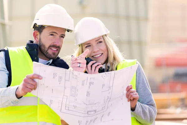 Workers on a construction studying blueprints — Stock Photo, Image