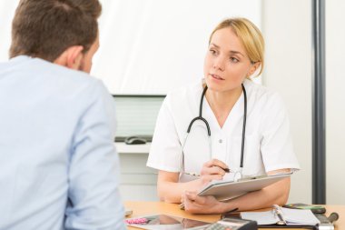 Genç çekici kadın doktor hasta sırasında not almak konuşmak