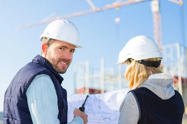 Dos trabajadores que trabajan fuera en una obra de construcción — Foto de Stock