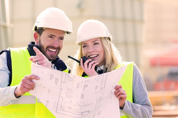 Arbeiter auf einer Baustelle studieren Baupläne — Stockfoto