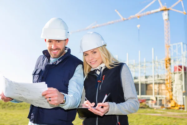 Dos trabajadores que trabajan fuera en una obra de construcción — Foto de Stock