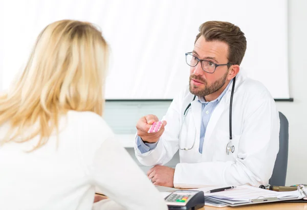 Młody atrakcyjny lekarz daje tabletki do pacjenta — Zdjęcie stockowe
