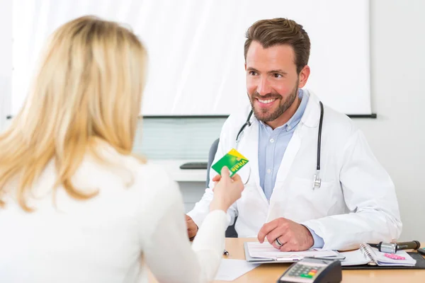 Joven médico atractivo tomando tarjeta de seguro de salud — Foto de Stock