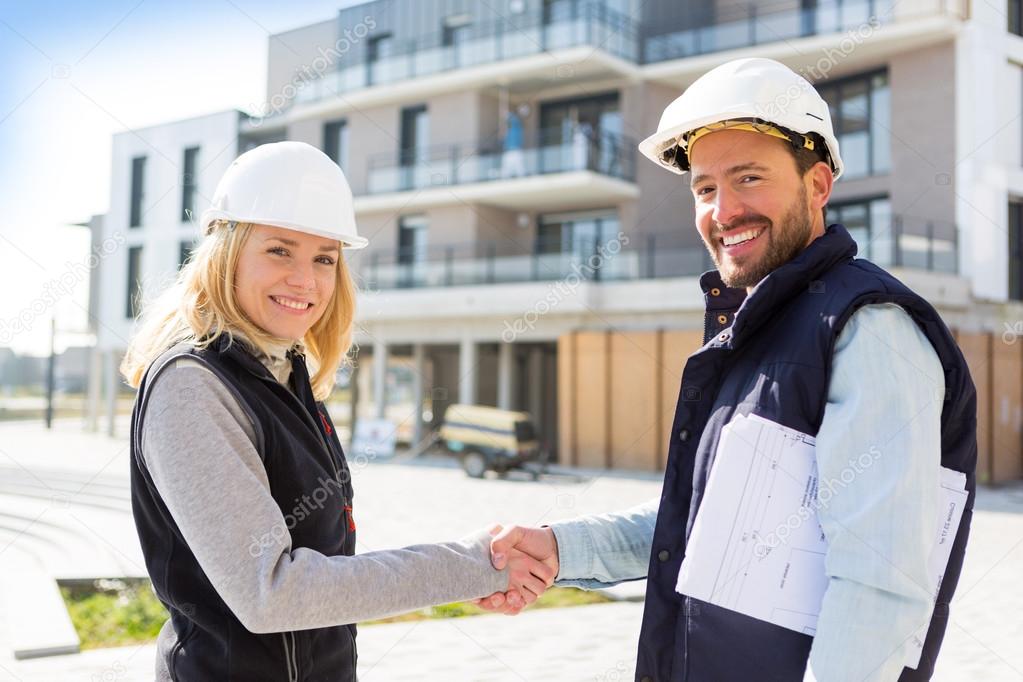 architect and worker handshaking on construction site 