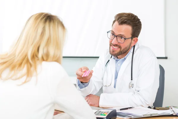 Młody atrakcyjny lekarz daje tabletki do pacjenta — Zdjęcie stockowe
