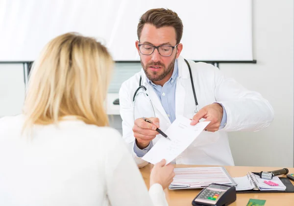 Unga attraktiva läkare ger recept till en patient — Stockfoto