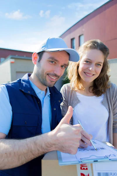 Young attractive woman signing on delivery paper — Stock Photo, Image