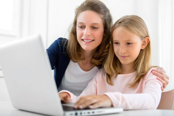 Attractive woman and little sister using laptop — Stock Photo, Image