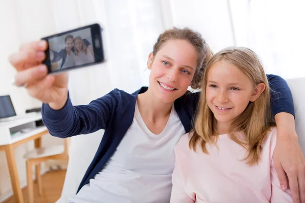 Attractive woman and little sister taking selfie — Stock Photo, Image