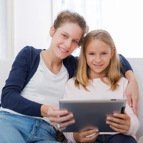 Attractive woman and little sister using tablet — Stock Photo, Image